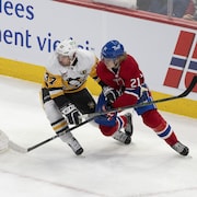 Un joueur de hockey enlève la rondelle à un joueur de l'équipe adverse.