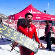 Le skieurs rit en tenant un panneau portant l'indication 255,5.