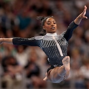 Une gymnaste fait un grand écart dans les airs.