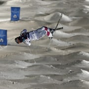 Un skieur acrobatique réalise une figure dans les airs.