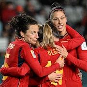 Trois joueuses de soccer s'étreignent sur le terrain.