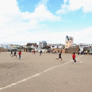 Des enfants jouent au soccer sur le sable.