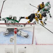 Un joueur de hockey est pris en photo au vol après avoir été trébuché en marquant un but.
