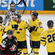 Des joueurs de la Suède, en jaune et bleu, célèbrent un but, alors que devant eux patine John Tavares, en noir et rouge. 