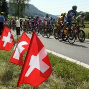 Les coureurs passent devant des petits drapeaux du pays, plantés au sol, durant le Tour de Suisse