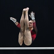 Une gymnaste effectue une manœuvre aux barres asymétriques. 