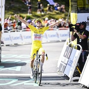 Un cycliste lève les bras au ciel en traversant la ligne d'arrivée d'une course.