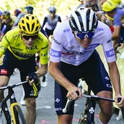 Jonas Vingegaard, en jaune, poursuit Tadej Pogacar, en blanc, tous deux sur leur vélo lors la 14e étape du Tour de France entre Annemasse et Morzine Les Portes du Soleil
