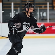 Une joueuse de hockey vêtue d'un chandail noir.