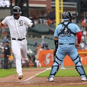 Un joueur de baseball atteint le marbre alors que le receveur attend la balle.