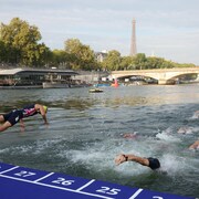 Des nageurs plongent, devant la tour Eiffel.