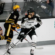Vincent Desharnais bloque un adversaire durant un match de hockey universitaire. 