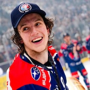Un hockeyeur portant une casquette tient un trophée dans ses mains.