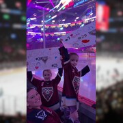 Deux jeunes partisanes de la Victoire montrent leur affiche devant la baie vitrée du Centre Bell.