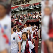 Les joueuses des Roses font leur entrée sur le terrain en tenant la main de jeunes.