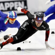Un patineur de vitesse sur courte piste effectue un virage devant un adversaire.