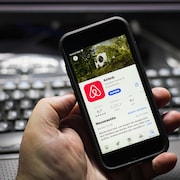 Un téléphone intelligent sur lequel on voit l'application d'Airbnb.