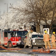 Des pompiers en action avec leurs camions garés sur les lieux d'un incendie.
