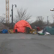 Des tentes sur un parking et des objets épars au sol. 