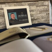 Une photo du sergent Eric Mueller, devant deux livres de condoléances à signer.