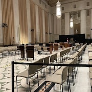Des chaises disposées en rangées de part et d'autre d'une pièce, avec un couloir presque vide où sied une table pour les greffiers, des lutrins et le fauteil du Président de la Chambre. 