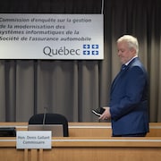 Denis Gallant marche en tenant un calepin et son téléphone cellulaire.