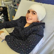 Une jeune fille avec un bandage autour de la tête est couchée dans un lit d'hôpital.
