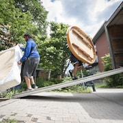 Un homme transporte un matelas et un autre transporte une table ronde à bord d'un camion de déménagement. 