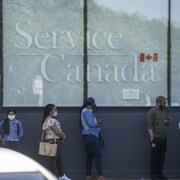 Sur la photo: (Gauche à droite) Une longue file d’attente aux bureaux de Service Canada, à Montréal, Québec. Passeport Canada.