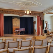 Une salle de réception et un piano sur une scène.