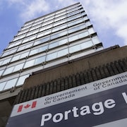Affiche du gouvernement fédéral devant un gratte-ciel vu en contre-plongé.