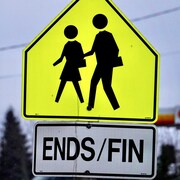 Panneau routier jaune représentant une traverse d'écoliers, avec les mots ENDS et FIN écrits en dessous.