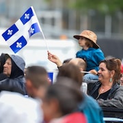 Des gens tiennent des drapeaux du Québec pour la Saint-Jean.