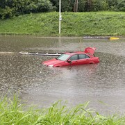 Une voiture submergée dans une rue inondée.