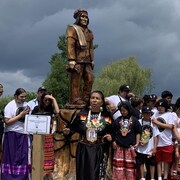 Des membres de la communauté autochtone se prennent en photo au pied de la statue de Tecumseh.