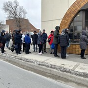 Des personnes font la file devant une boulangerie.