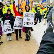 Des postiers en grève qui manifestent sous la pluie. 