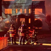pompiers en action devant un bâtiment en feu. 