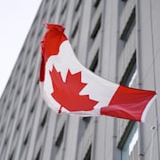 Le drapeau du Canada flotte devant un édifice.