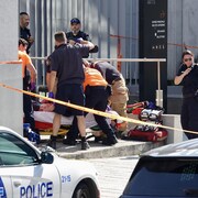 Des policiers et des ambulanciers viennent en aide à une personne inconsciente venant d'être poignardé dans le centre-ville de Montréal.