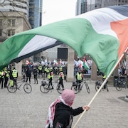 Un manifestant agite un drapeau palestinien devant une rangée de policiers.
