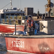 Un membre d'équipage à bord d'un homardier sourit en direction du photographe.