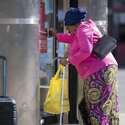 Une dame âgée pousse la porte d'un commerce.