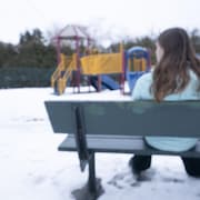 Une enfant est assise sur un banc de parc.