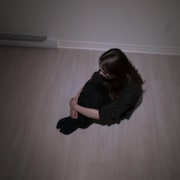 Une jeune fille seule est assise au sol.
