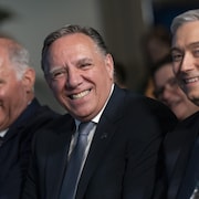 Les trois hommes sourient.