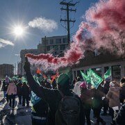 Plusieurs dizaines de personnes marchant dans la rue, drapeaux à la main.