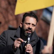 Haroun Bouazzi parlant dans un micro &agrave; l'ext&eacute;rieur.