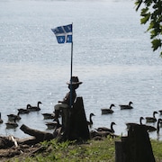 Waterfront with ducks and Quebec flag.