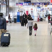 Des voyageurs transportant leurs valises à l'aéroport.